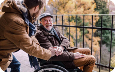 A man in a wheelchair being assisted by a caregiver.