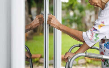 Elderly woman with key opening front door.