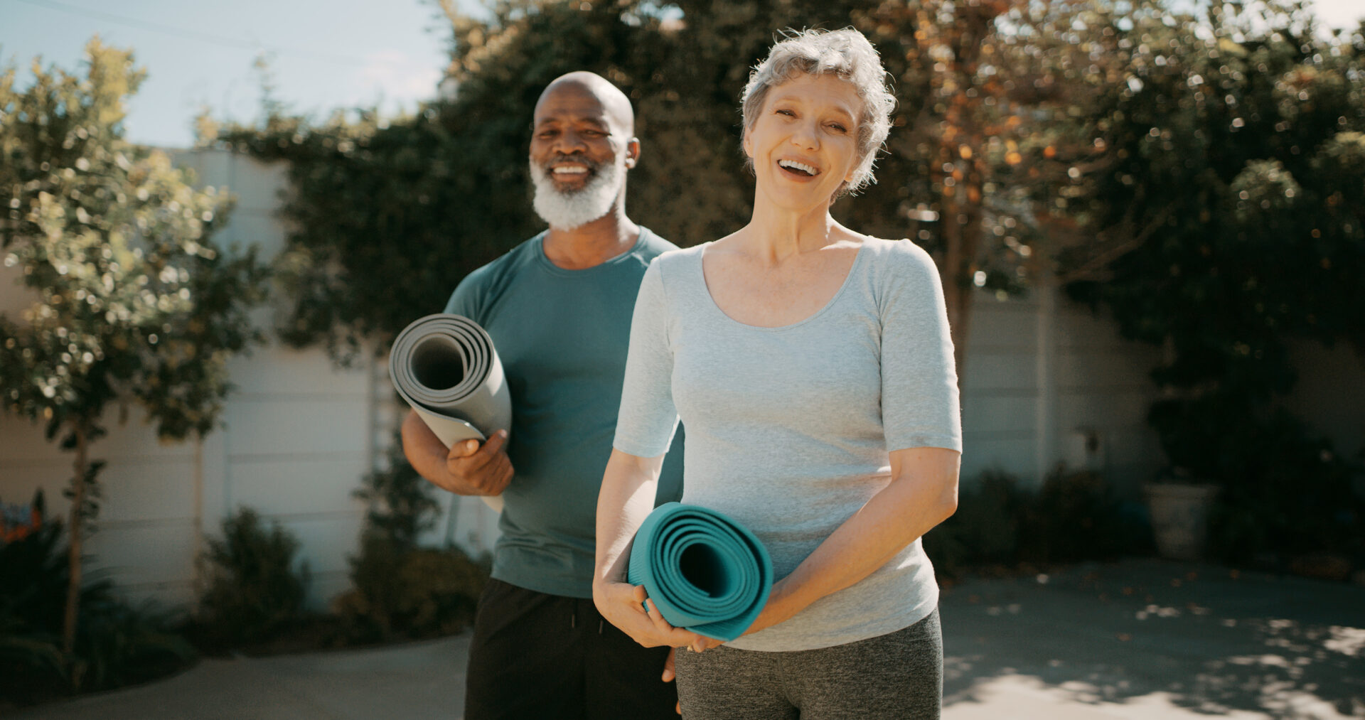 Happy senior couple ready for a back garden yoga session.
