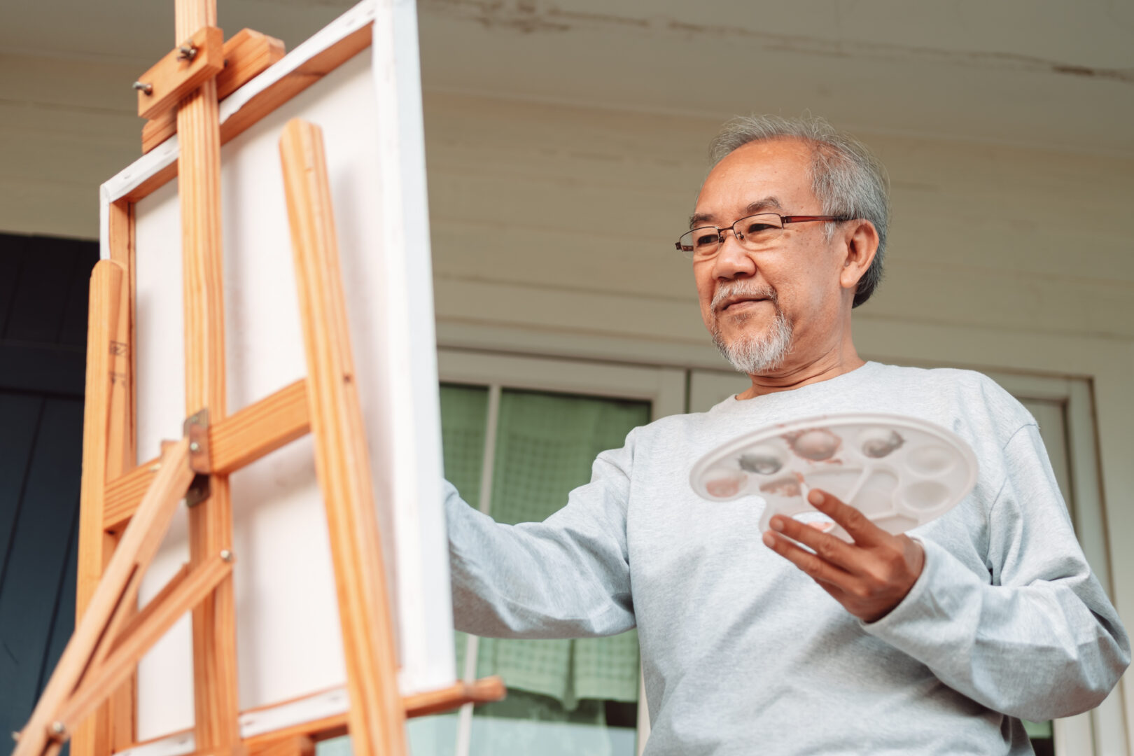 Social Activities for Seniors An Asian senior artist painting a vibrant artwork, showcasing creativity, passion, and cultural expression through art