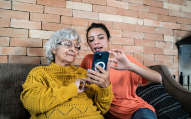 Granddaughter helping grandmother to use the mobile phone at home