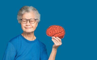 Portrait of a senior woman holding a brain symbol while standing on a blue background