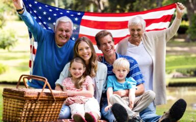 Multi-generation family holding american flag in the park