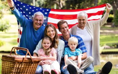 Multi-generation family holding american flag in the park