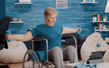 Senior adult sitting in wheelchair and doing exercise with weights
