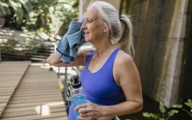 Caucasian older woman wiping sweat and cooling off after sports training