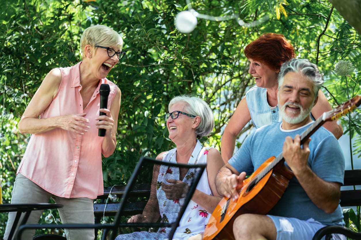 Group of elderly people enjoying their retirement by going on a picnic, playing a guitar and singing, making barbeque, making memories and making their friendship stronger