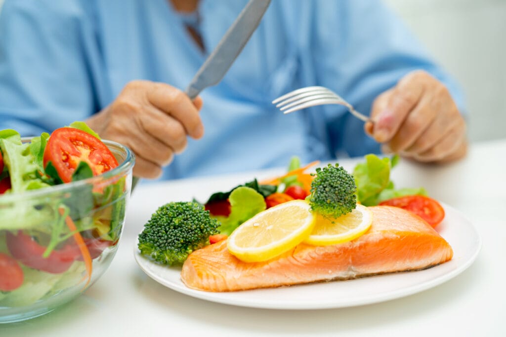 Elderly woman eating salmon steak breakfast with vegetable healthy food for immune health