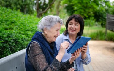 Cheerful elderly woman quickly studies to use the tablet to communicate in social networks