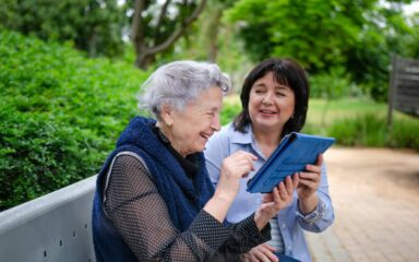 Cheerful elderly woman quickly studies to use the tablet to communicate in social networks