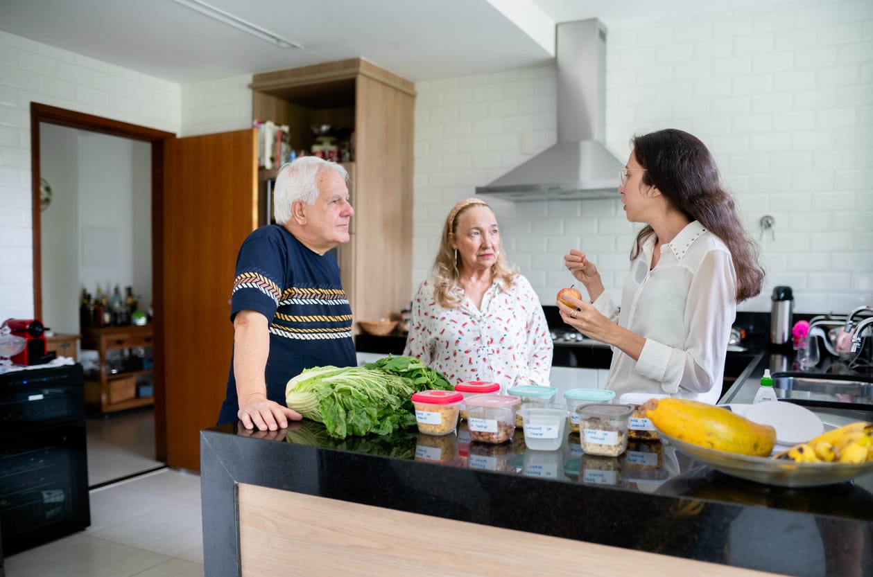 Cooking Tips: Preserve Calcium for Elderly Health Young female nutritionist and a senior couple discussing food options at their kitchen counter during a diet consultation.