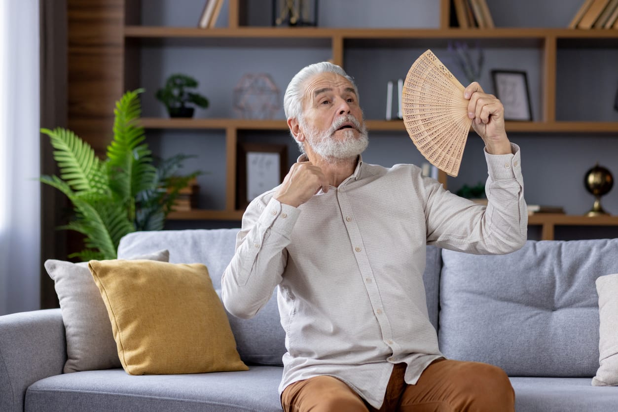 Elderly man fanning himself to take preventive measures for elderly in hot weather.