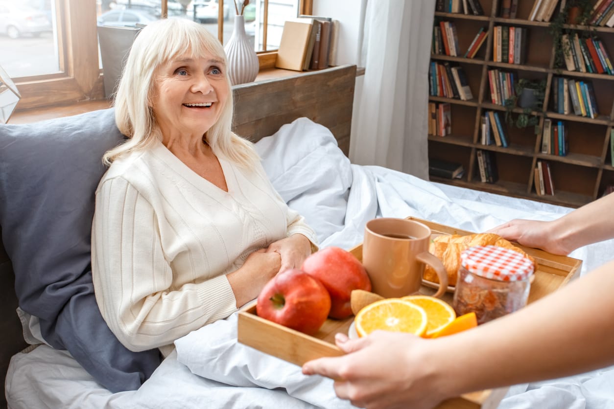 A young nurse provides a nutritious breakfast to a senior woman at home, featuring fresh fruits, pastries, and tea, symbolising compassionate in-home care and the importance of a balanced diet for well-being. Assisted Living Locators supports seniors and their families in finding personalized home care solutions for a healthier, happier lifestyle.