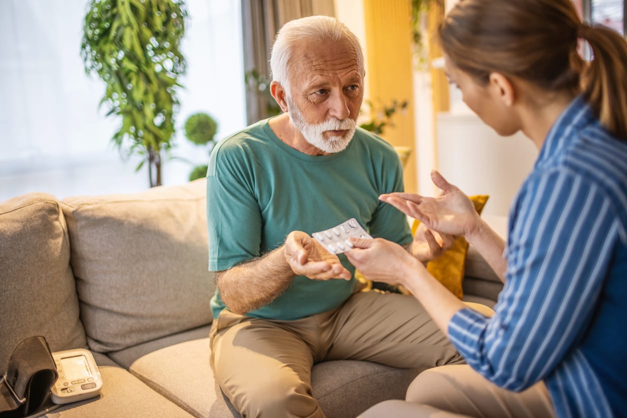 World Heart Day: Essential Tips for Elderly Heart Health. Photo of young woman spending time with her old father, give him some medicine at home.