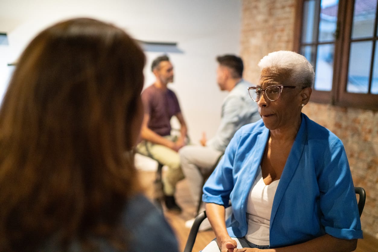 Protect Senior Rights: Health Care, Social Security, & Abuse Prevention. A senior woman engaged in a conversation, highlighting the importance of safeguarding seniors’ rights, access to healthcare, financial security, and protection from abuse.