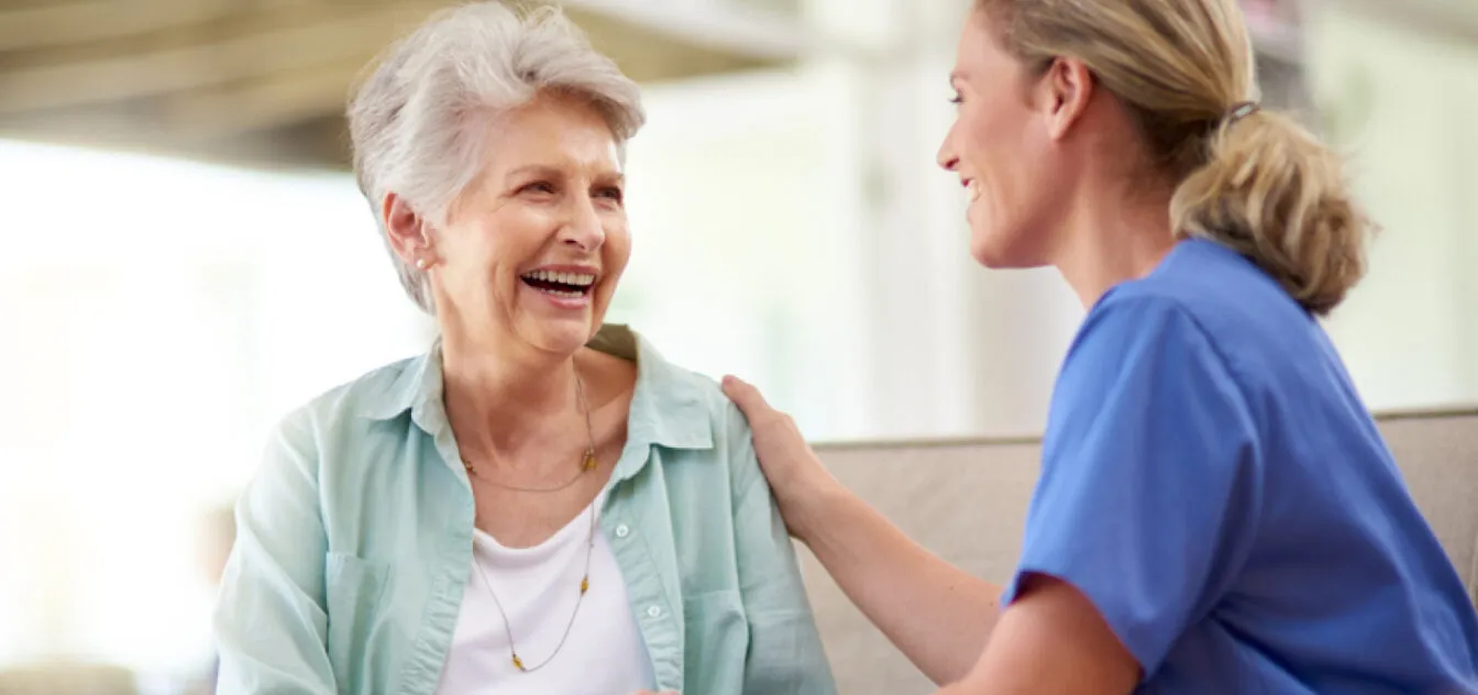 A nurse comforts her patient with a smile and a warm touch.